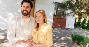 Couple standing outside their home smiling, representing high-income family retirement planning