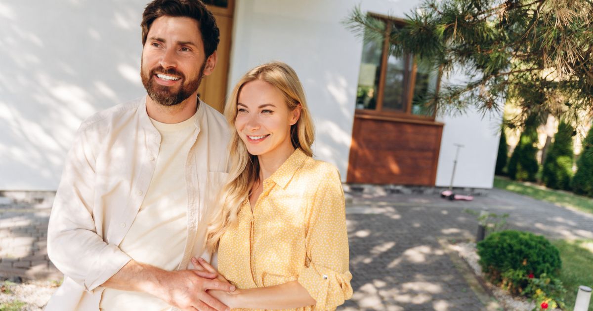 Couple standing outside their home smiling, representing high-income family retirement planning
