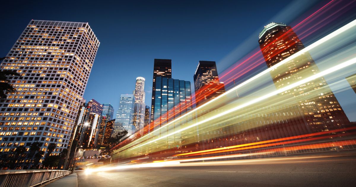 Long-exposure city skyline at night with light trails representing speed and technological momentum